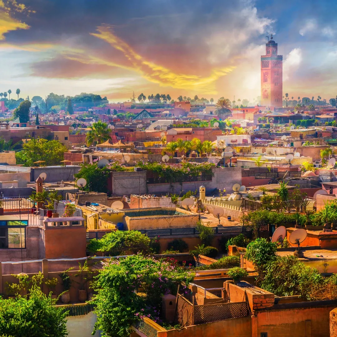 Plaza Jemaa el-Fna en Marrakech, Marruecos, con mercados tradicionales y la Mezquita Koutoubia iluminada al atardecer.
