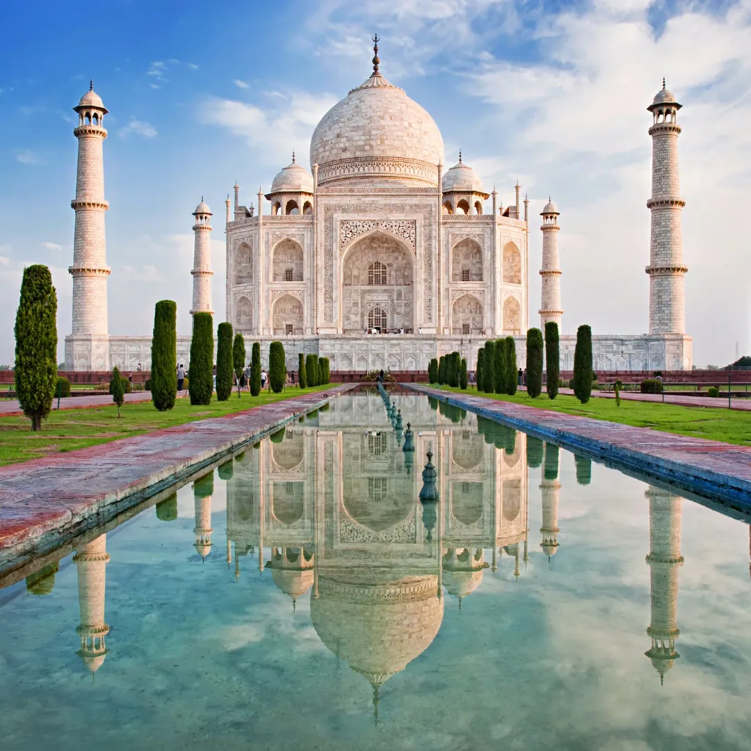 Taj Mahal en Agra, India, majestuoso monumento de mármol blanco rodeado de jardines y estanques reflectantes.